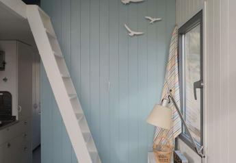 Interno luminoso di casa sulla spiaggia con parete blu, scala bianca e decorazioni di uccelli a Zeeland, Paesi Bassi.