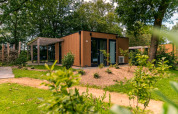 Modern Cube lodge at EuroParcs Ruinen in the Netherlands, surrounded by greenery and trees outdoors.