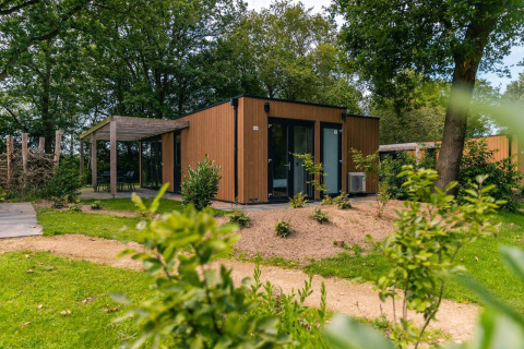 Moderne Cube lodge bij EuroParcs Ruinen in Nederland, omgeven door groen en bomen in de natuur.