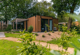 Moderne Cube-Lodge bei EuroParcs Ruinen in den Niederlanden, umgeben von Natur und Bäumen.
