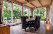 Modern dining room with large windows and garden view at Cube lodge in EuroParcs Ruinen, Netherlands.