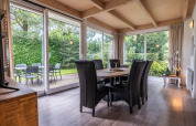 Comedor moderno con grandes ventanales y vistas al jardín en Cube lodge de EuroParcs Ruinen, Países Bajos.