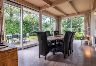 Sala da pranzo moderna con grandi finestre e vista sul giardino al Cube lodge di EuroParcs Ruinen, Olanda.