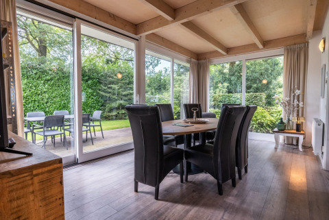 Sala da pranzo moderna con grandi finestre e vista sul giardino al Cube lodge di EuroParcs Ruinen, Olanda.