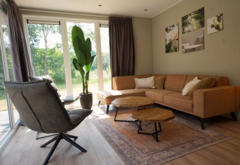 Lichte moderne woonkamer in Cube lodge bij EuroParcs Ruinen, Nederland, met hoekbank en grote ramen.