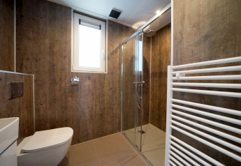 Moderne badkamer met houtlook wanden, glazen douche en raam in Cube bij EuroParcs Ruinen, Nederland.