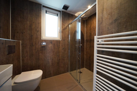 Moderne badkamer met houtlook wanden, glazen douche en raam in Cube bij EuroParcs Ruinen, Nederland.