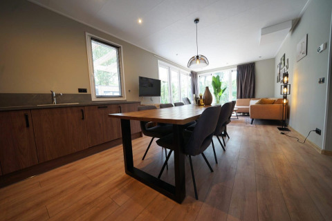 Moderne lodge med åbent køkken, spisebord og hyggelig stue hos EuroParcs Ruinen i Nederlandene.