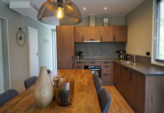 Cucina moderna e zona pranzo nel Cube lodge presso EuroParcs Ruinen, Paesi Bassi, con finiture in legno.