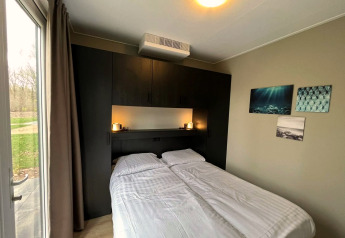 Moderne lodge-slaapkamer bij Cube in EuroParcs Ruinen, Nederland, met tweepersoonsbed en groot raam.