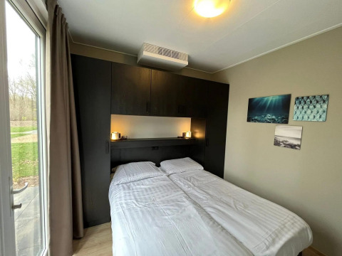 Modernes Schlafzimmer in der Cube Lodge im EuroParcs Ruinen, Niederlande, mit Doppelbett und Fenster.