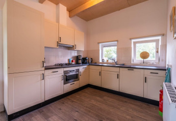 Modern kitchen layout in a Cube lodge at EuroParcs Ruinen, Netherlands with light cabinets and appliances.