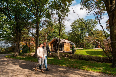 Una pareja pasea frente a una tiny house en EuroParcs Ruinen, Países Bajos, rodeados de naturaleza.