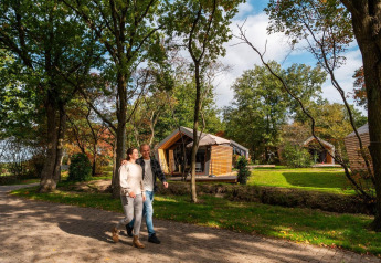 Koppel wandelt bij een tiny house in EuroParcs Ruinen in Nederland, omringd door bomen en natuur.
