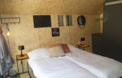 Dormitorio en la tiny house Solo Retreat de EuroParcs Ruinen, Países Bajos, con cama doble y decoración moderna.