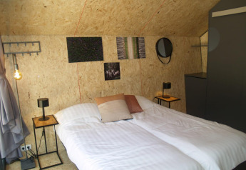 Slaapkamer in de Solo Retreat tiny house bij EuroParcs Ruinen, Nederland, met tweepersoonsbed en moderne inrichting.