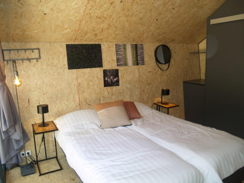 Camera da letto nel tiny house Solo Retreat a EuroParcs Ruinen, Paesi Bassi, con letto matrimoniale e arredo moderno.