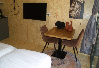 Sfeervol Solo Retreat tiny house bij EuroParcs Ruinen met tafel, tv en warme inrichtingselementen.