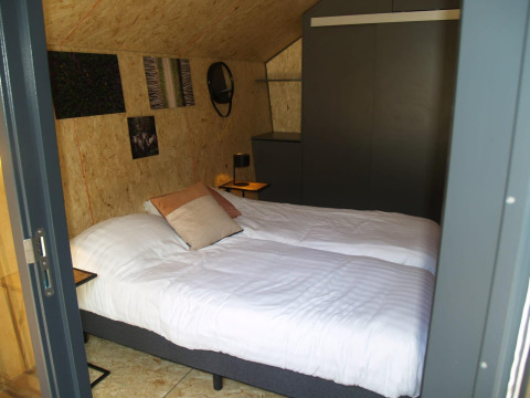 Camera accogliente nella tiny house Solo Retreat presso EuroParcs Ruinen, Paesi Bassi, con due letti singoli.