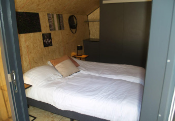Dormitorio acogedor en la tiny house Solo Retreat en EuroParcs Ruinen, Países Bajos, con dos camas individuales.