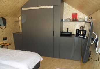 Moderne tiny house Solo Retreat bij EuroParcs Ruinen in Nederland met bed, keuken en televisie.