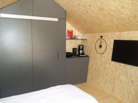 Interior de una tiny house en Solo Retreat, EuroParcs Ruinen, con cama, armario, cafetera y televisor.