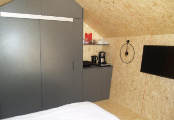 Interiør af et lille hus ved Solo Retreat, EuroParcs Ruinen, med seng, skab, kaffemaskine og tv.