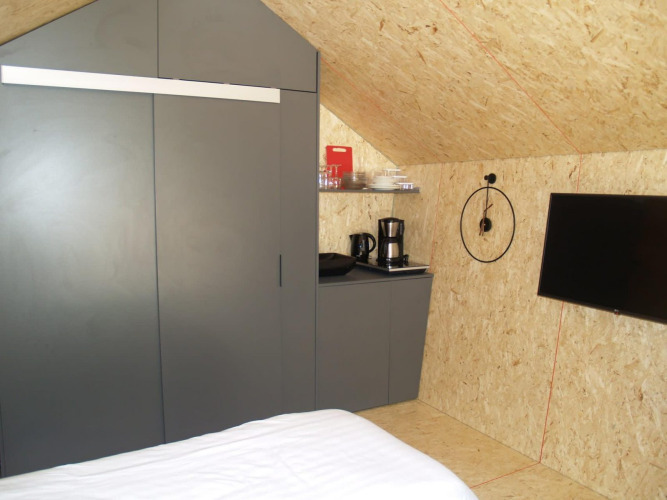 Innenraum eines Tiny House im Solo Retreat, EuroParcs Ruinen, mit Bett, Schrank, Kaffeemaschine und TV.