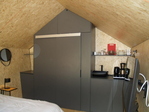 Interior moderno de tiny house con armarios grises, cafetera y menaje de cocina en EuroParcs Ruinen, Países Bajos.