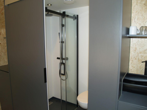 Baño moderno con ducha y aseo en una tiny house Solo Retreat en EuroParcs Ruinen, Países Bajos.