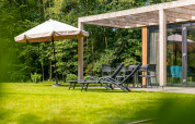 Sunny garden terrace at Cube Hot tub lodge, EuroParcs Ruinen, Netherlands, with loungers and garden furniture.