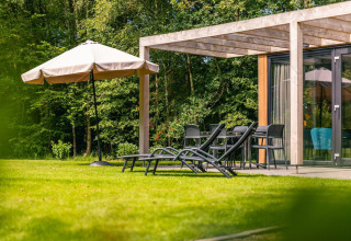 Sunny garden terrace at Cube Hot tub lodge, EuroParcs Ruinen, Netherlands, with loungers and garden furniture.