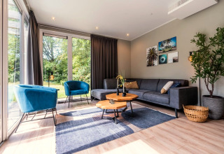 Moderne woonkamer met blauwe stoelen en grijze bank in Cube Hot tub lodge bij EuroParcs Ruinen.
