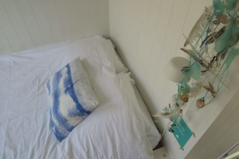Bright bedroom with white bedding, blue beach-themed pillow and coastal decor at Beach house Dishoek 60.