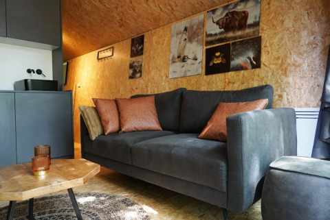 Zona giorno del tiny house Solo Retreat a EuroParcs Ruinen nei Paesi Bassi, con divano e decorazioni.