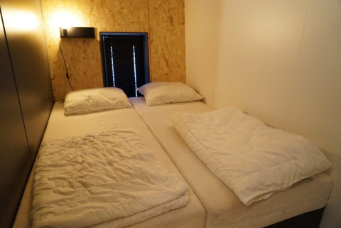 Due letti singoli in una piccola stanza minimalista al Solo Retreat di EuroParcs Ruinen, Paesi Bassi.
