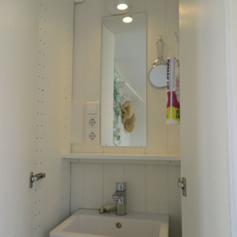 Pequeño lavabo de baño con espejo y estante en Beach house 'Dishoek 60', Dishoek, Zeeland, Países Bajos.