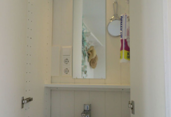 Kleine badkamerwastafel met spiegel en plank in Beach house 'Dishoek 60', Dishoek, Zeeland, Nederland.