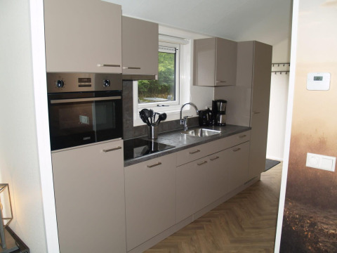 Moderne keuken in Velthorst lodge bij EuroParcs Ruinen in Nederland, met beige kasten en toestellen.