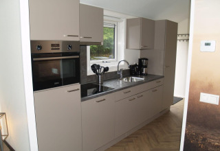 Moderne keuken in Velthorst lodge bij EuroParcs Ruinen in Nederland, met beige kasten en toestellen.