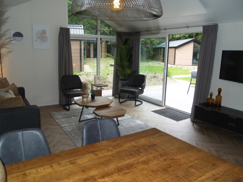 Moderne lodge leefruimte met grote ramen en zicht op tuin bij Velthorst in EuroParcs Ruinen, Nederland.