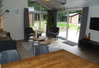 Moderne lodge leefruimte met grote ramen en zicht op tuin bij Velthorst in EuroParcs Ruinen, Nederland.