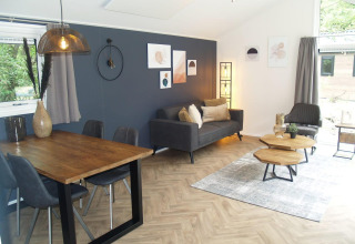 Zona giorno e pranzo moderna nella lodge Velthorst presso EuroParcs Ruinen, Paesi Bassi, con arredi eleganti.