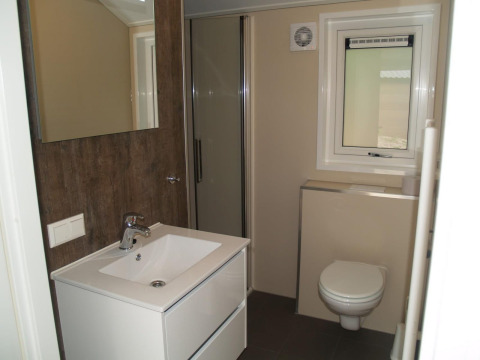 Moderne badkamer met witte wastafel, spiegel, douche en raam in Velthorst lodge bij EuroParcs Ruinen.