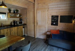 Soggiorno e cucina accoglienti nel lodge Drentse kap a EuroParcs Ruinen, Paesi Bassi, con arredo in legno.