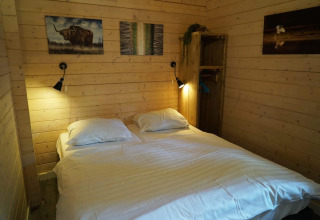 Camera da letto con letto matrimoniale, pareti in legno, lampade e arte al Drentse kap, EuroParcs Ruinen, Paesi Bassi.