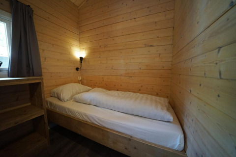 Habitación pequeña y acogedora con paredes de madera y cama individual en Drentse kap, EuroParcs Ruinen, Países Bajos.