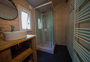 Moderne badeværelse med trægulve, brusekabine, vask og vindue i Drentse kap ved EuroParcs Ruinen.