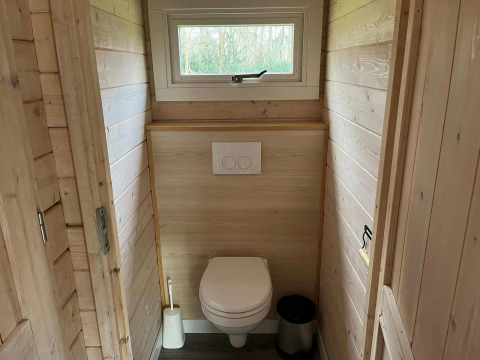 Baño con paredes de madera y ventana pequeña en una cabaña de Drentse kap, EuroParcs Ruinen, Países Bajos.