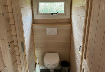 Baño con paredes de madera y ventana pequeña en una cabaña de Drentse kap, EuroParcs Ruinen, Países Bajos.